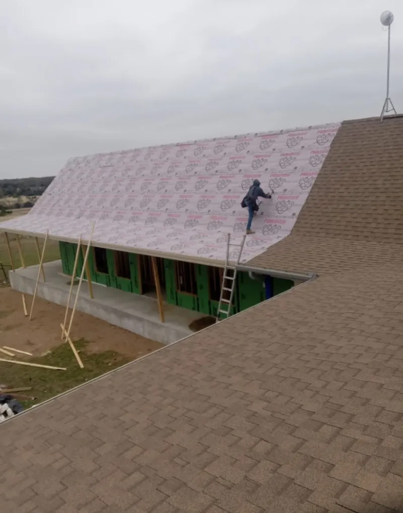 Worker preparing underlayment for a metal roof installation in Mullica